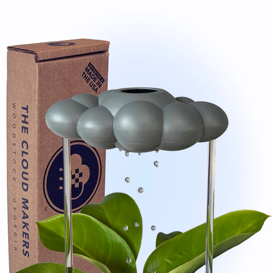 A gray 'Stormy Dripping Rain Cloud' plant watering cloud with water droplets, displayed next to its packaging box with 'THE CLOUD MAKERS' branding.