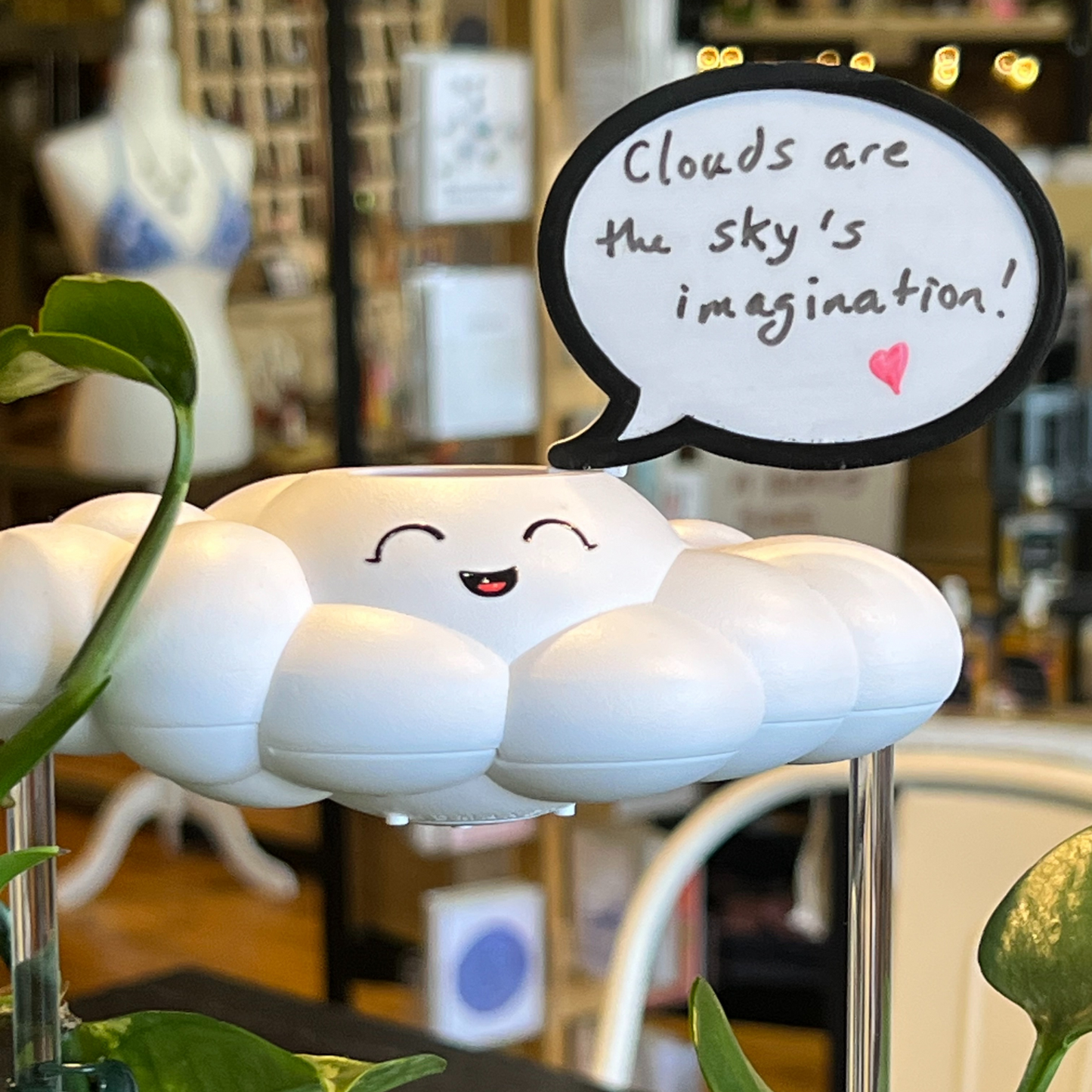 Chelsea the Cloud with a smiling face and a speech bubble with text in a store setting