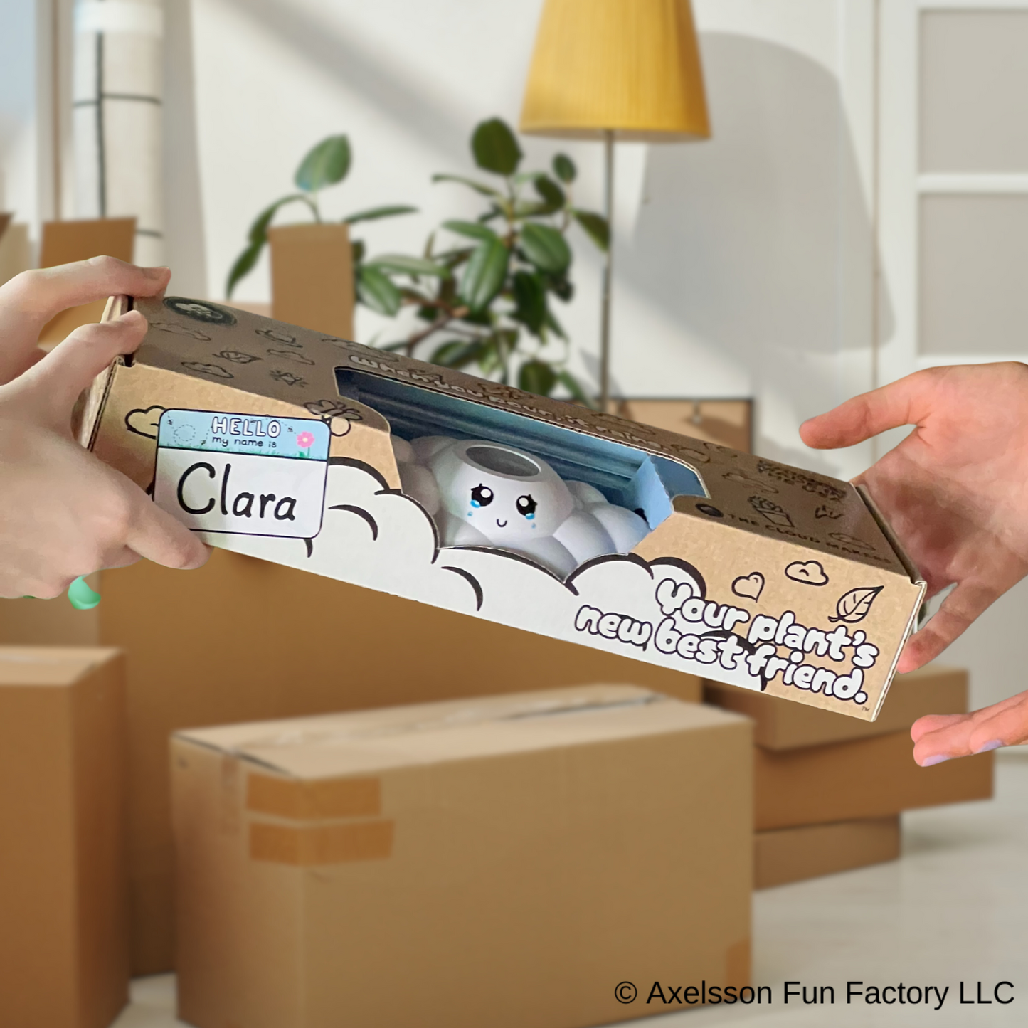 Clara the cloud in product packaging, held by two hands in a room setting.