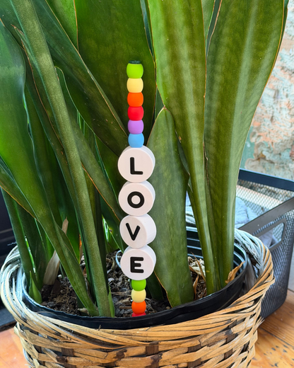 Potted plant with a decorative item spelling 'LOVE' among its leaves.
