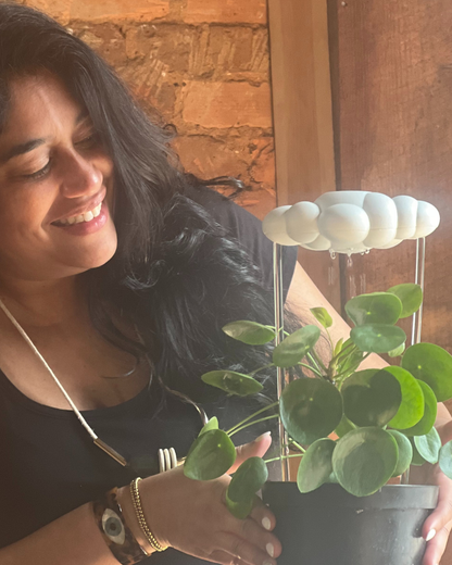 Woman holding a potted plant with original dripping rain cloud with a brick wall background