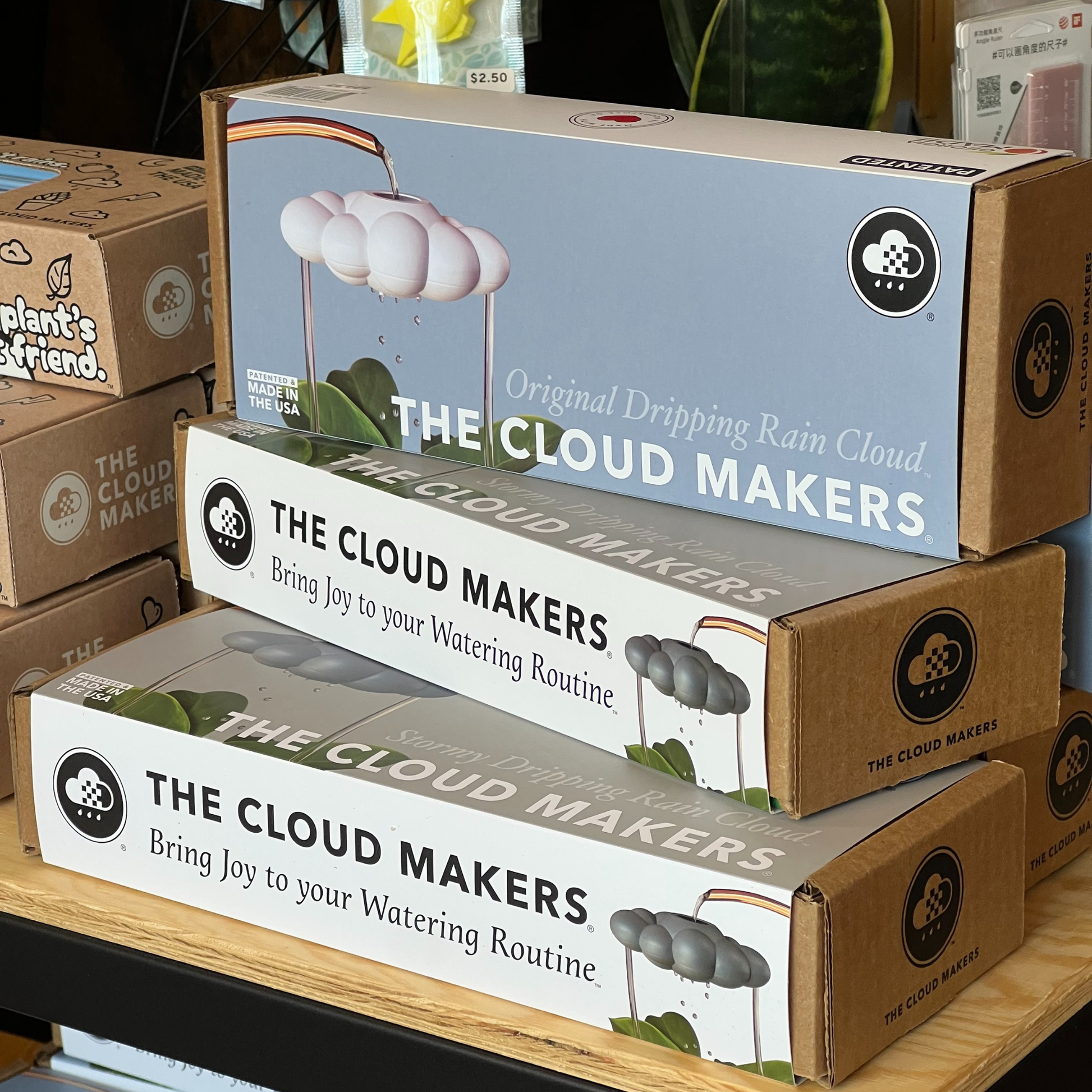 Boxes of 'The Cloud Makers' product stacked on a wooden surface.