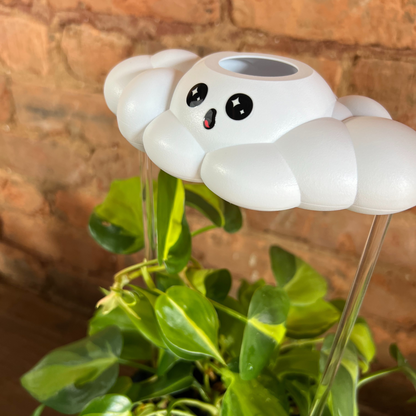 Cosmo the Cloud on top of a plant against a brick wall.