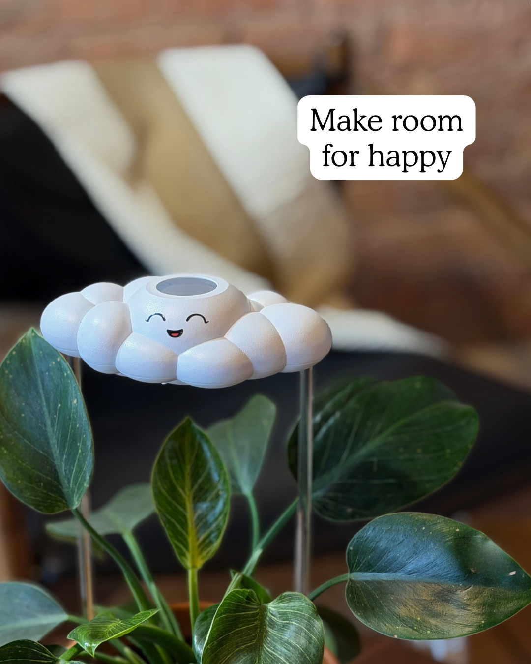 Chelsea the Cloud on top of a plant, with text 'Make room for happy' in the background.